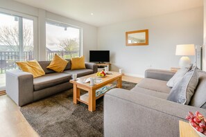 A modern living room with a grey sofa set, a coffee table, and a flat-screen TV. - 4 Bed in Winnards Perch (oc-k30259) (Winnard's Perch)