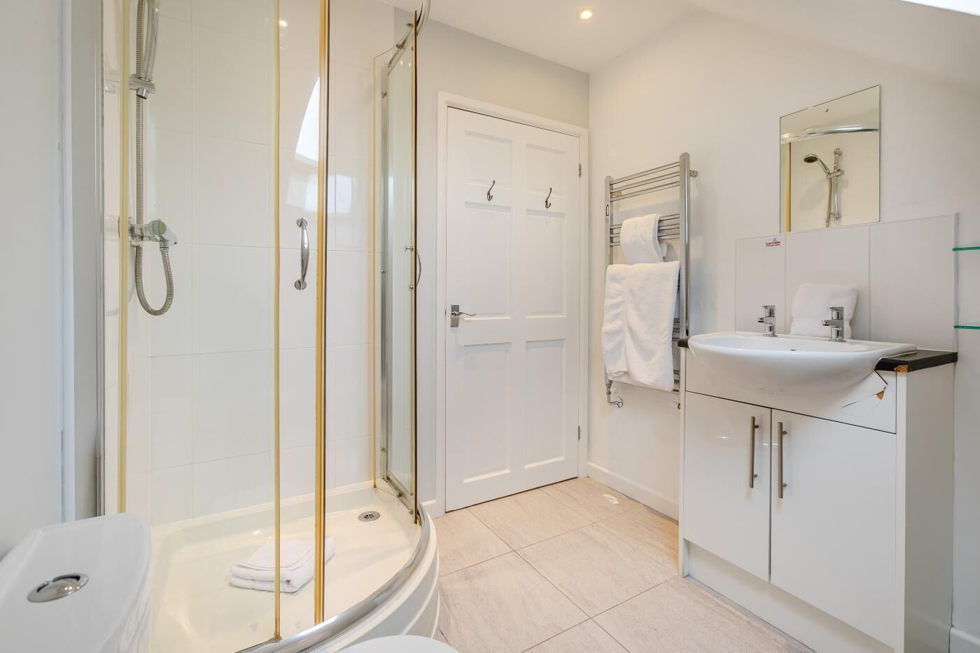 A modern bathroom with a glass-enclosed shower, a white sink, and a toilet.