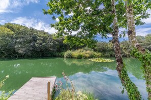 A calm lake with a wooden dock extending into the water, surrounded by lush greenery and trees. - 4 Bed in Winnards Perch (oc-k30259) (Winnard's Perch)