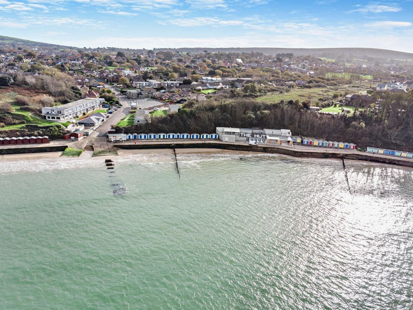 A coastal town with a prominent hotel named 'The Hut' featuring a waterfront promenade and a train station.