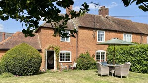 A brick house with a garden, a patio with wicker furniture, and a green umbrella. - 2 Bed in Nacton (oc-c30257) (Nacton)