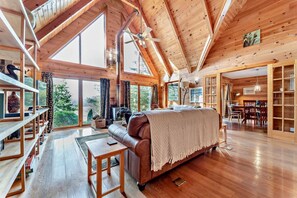 A spacious cabin with a high ceiling, wooden walls, and large windows offering a view of the outdoors. - 3 Bed in Kippford (oc-g30100) (Kippford)