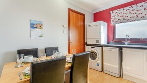 Eine kompakte Küche mit Essbereich, einer Waschmaschine, einem Geschirrspüler und einem Kalender an der Wand.