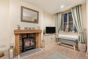 A cozy living room with a fireplace, a television, and a bench by the window. - 3 Bed in Whitby (oc-p30284) (Whitby)