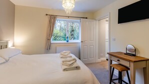 A bedroom with a bed, a desk, a chair, a chandelier, a window with curtains, and a door. - 3 Bed in Wilberfoss (oc-t30301) (Wilberfoss)