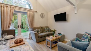 A cozy living room with a dining area, a large window, and a flat-screen TV on the wall. - 3 Bed in Wilberfoss (oc-t30301) (Wilberfoss)