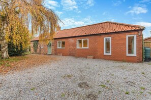A brick house with a tiled roof, a gravel driveway, and a tree with autumn leaves. - 3 Bed in Wilberfoss (oc-t30301) (Wilberfoss)