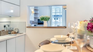 Eine moderne Küche mit Einbauofen, ein Essbereich mit Stadtblick und ein Fenster mit Pflanze.