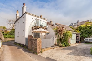 A white two-story house with a balcony, a small garden, and a shed. - 3 Bed in Thurlestone (oc-h30263) (Thurlestone Sands)