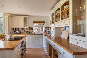 A kitchen with white cabinetry, wooden countertops, a tiled backsplash, and a window with a view. - 3 Bed in Beaminster (oc-t30165) (Beaminster)