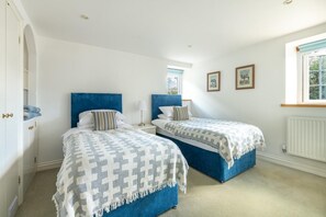 A bedroom with two beds, a wardrobe, a window with a view, and a radiator.