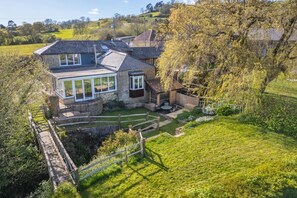 A two-story house with a large glass conservatory, a wooden deck, and a fenced garden. - 3 Bed in Beaminster (oc-t30165) (Beaminster)