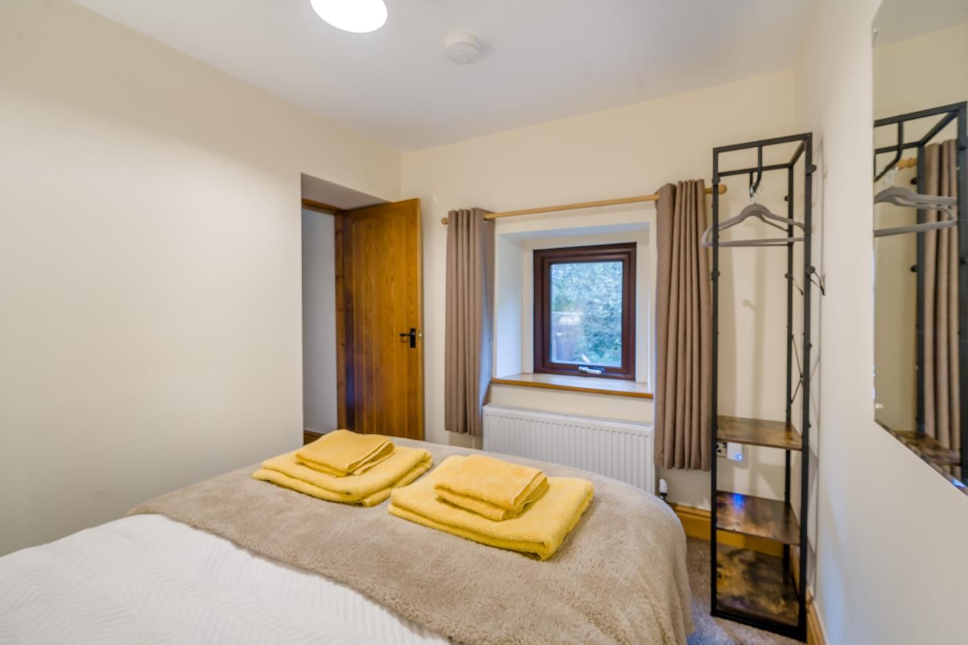 A bedroom with a bed, a window, a radiator, and a wardrobe.