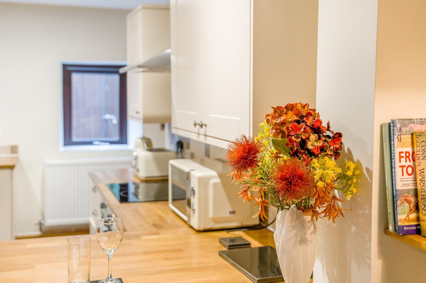 A modern kitchen with white cabinets, a toaster, and a vase of flowers on the counter.