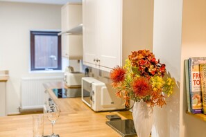 A modern kitchen with white cabinets, a toaster, and a vase of flowers on the counter. - 2 Bed in Oakenclough (oc-m30216) (Oakenclough)