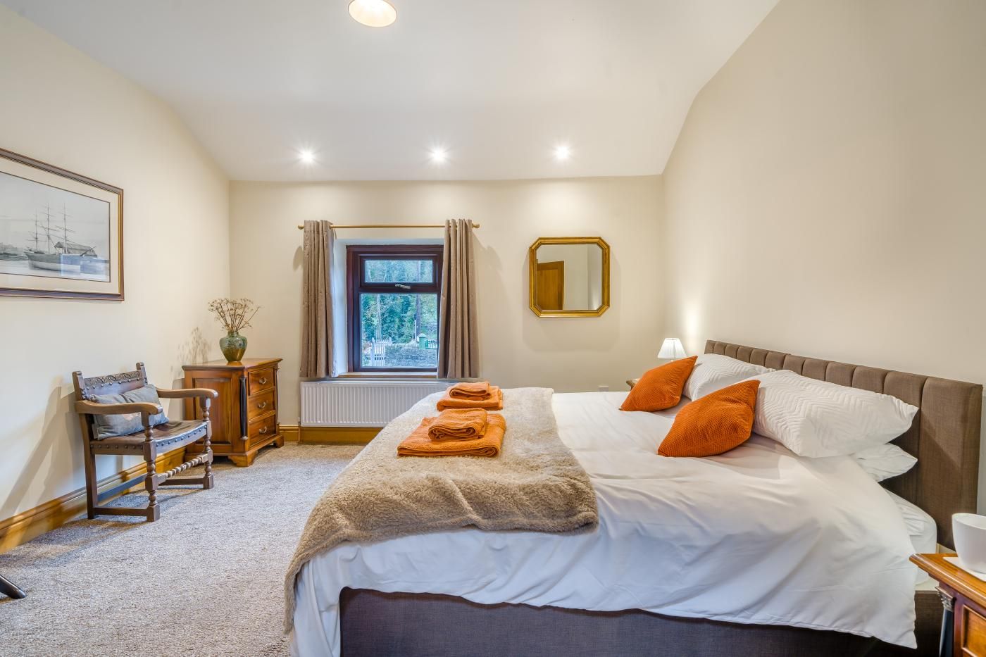 Une chambre à coucher avec un lit, une chaise, une commode, une fenêtre et un miroir.