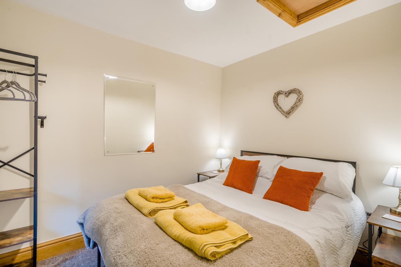 Een hotelkamer met een bed, een spiegel, een decoratie in de vorm van een hart en handdoeken.