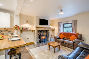 A living room with a fireplace, a sofa, a coffee table, and a television mounted on the wall. - 2 Bed in Oakenclough (oc-m30216) (Oakenclough)