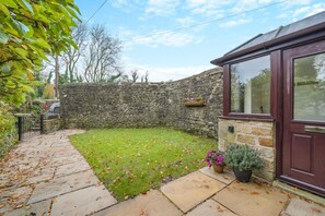 A stone wall, a paved pathway, a grassy yard, and a wooden door. - 2 Bed in Oakenclough (oc-m30216) (Oakenclough)