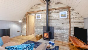 Ein gemütliches Schlafzimmer im Loft-Stil mit Steinwand, Kamin, Fernseher und einer bequemen Sitzecke.