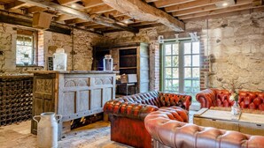 Ein rustikales Interieur mit freiliegenden Holzbalken, Steinwänden, einer Holzbar und Ledersitzmöbeln.