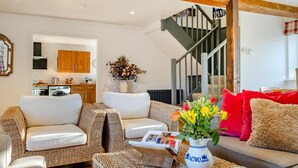 Ein gemütliches Wohnzimmer mit einer Couch, einem Couchtisch mit einer Vase und einer Treppe.