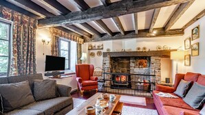 A cozy living room with exposed wooden beams, a stone fireplace, and comfortable seating.
