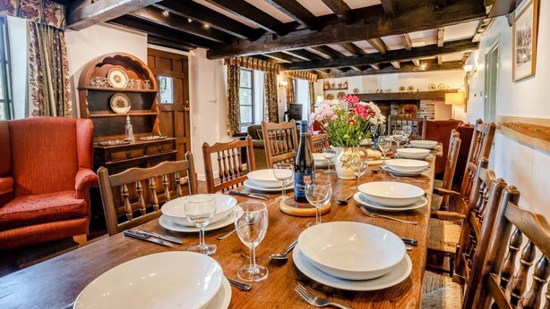 A dining room with a wooden table set for a meal, surrounded by wooden chairs.