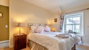 A neatly arranged bedroom with a large bed, two bedside lamps, a window with curtains, and a view of the outside. - 3 Bed in Swanage (oc-s30316) (Swanage)