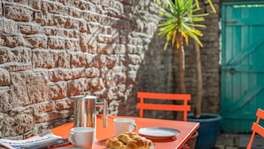 A table set outdoors with a brick wall, a green gate, and a potted plant in the background. - 3 Bed in Swanage (oc-s30316) (Swanage)