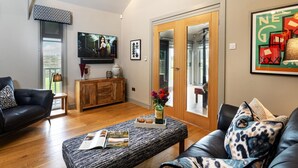 Ein modernes Wohnzimmer mit Flachbildfernseher, Holzschrank und bequemen Sitzgelegenheiten.