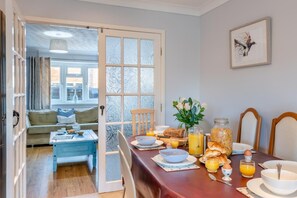 Un coin repas avec une table mise pour le petit-déjeuner, comprenant du pain, des œufs et du jus d’orange.