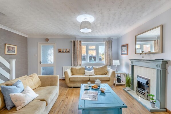 Un salon chaleureux avec un canapé beige, une table basse bleue et une cheminée.