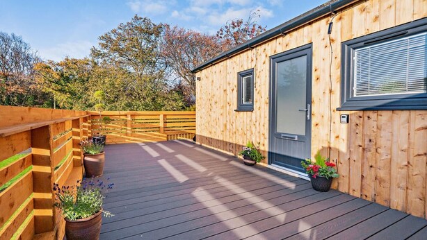 Eine Holzhütte mit einer Terrasse, einer Tür und Topfpflanzen.