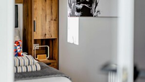 Ein Schlafzimmer mit einem Bett, einem Holzschrank, einem Schreibtisch mit Stuhl und einem Wandbild.