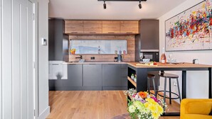 Eine moderne Küche mit Holzschränken, einem eingebauten Ofen und einem Essbereich mit einem gelben Stuhl und einem Tisch.