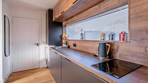 Eine moderne Küche mit Holzausstattung, einem eingebauten Ofen und einem Fenster mit Jalousien.