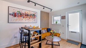 Ein modernes Wohnzimmer mit Essbereich, einem großen abstrakten Gemälde, einer Couch und einem kleinen Tisch mit Blumen in einer Vase.