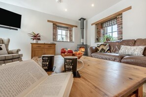 A cozy living room with a fireplace, a wooden table, and a sofa. - 3 Bed in Llanddarog (oc-p30291) (Llanddarog)
