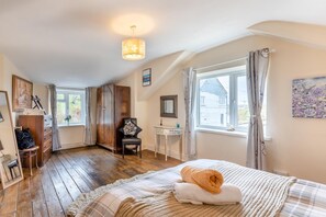 A bedroom with a wooden floor, a bed with a white and beige blanket, a chair, a desk, a wardrobe, and a window with curtains. - 2 Bed in Rogerscale (oc-m30396) (Blindbothel)