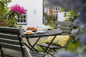 A round wooden table with a white teapot, a cup, and a plate of strawberries. - 1 Bed in Bridport (oc-p30346) (Bridport)