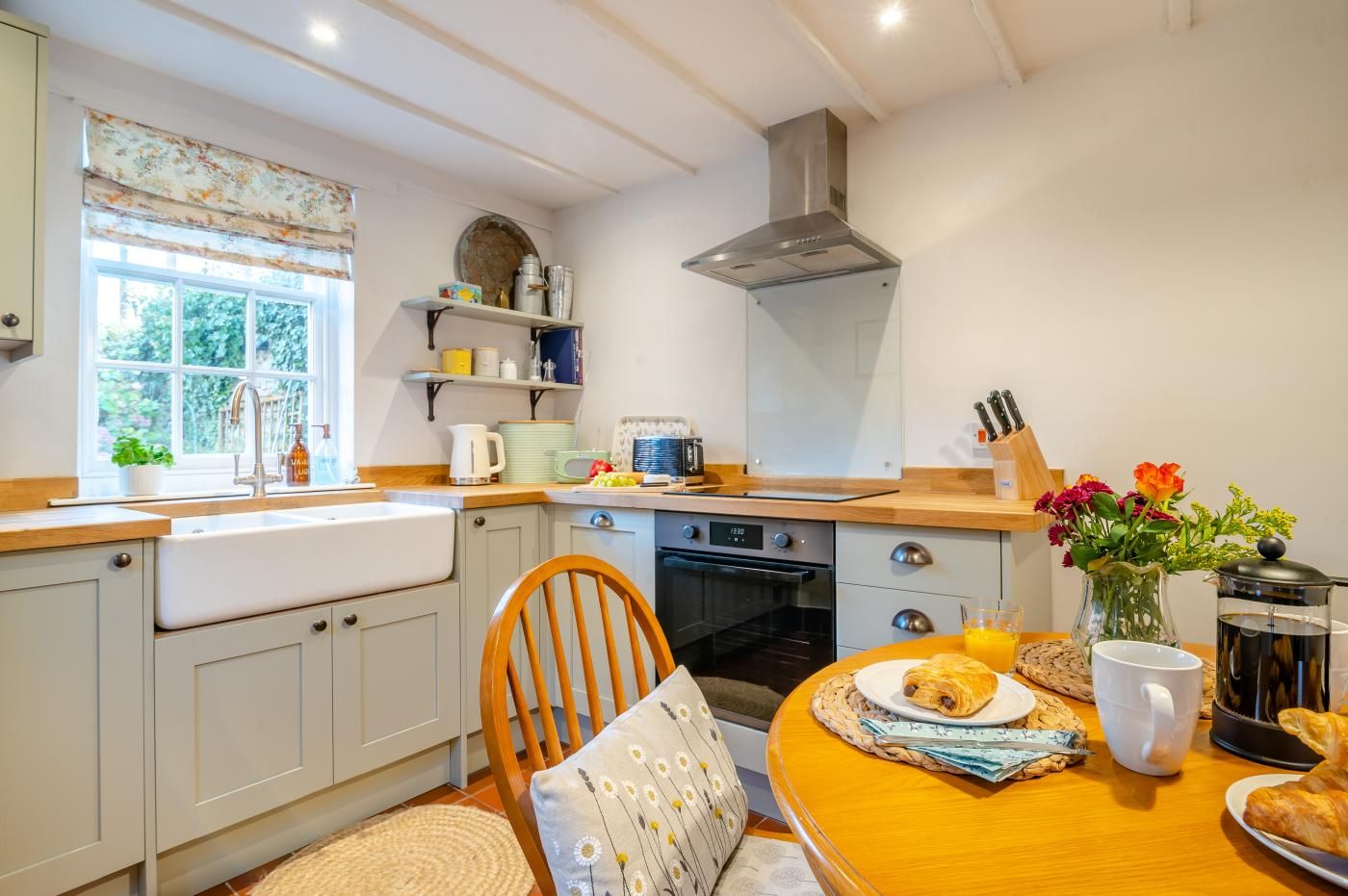 A kitchen with a wooden countertop, a sink, a stove, and a window with blinds.