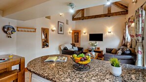 A cozy living room with a fireplace, a television, and a dining area with a granite countertop and a bowl of fruit. - 2 Bed in Ellastone (oc-t30011) (Ellastone)