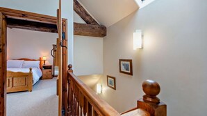 A bedroom with a wooden bed, bedside table, and lamp, a staircase with wooden balusters, and a skylight. - 2 Bed in Ellastone (oc-t30011) (Ellastone)