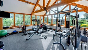 A gym with exercise equipment, large windows, and a view of greenery. - 2 Bed in Ellastone (oc-t30011) (Ellastone)