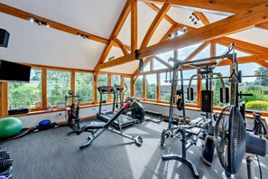A gym with exercise equipment, large windows, and a view of greenery. - 1 Bed in Ellastone (oc-t30012) (Ellastone)