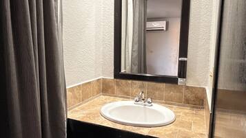 A bathroom with a sink, mirror, and shower curtain.
