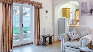 A living room with a grey sofa, a small table, and a window with curtains. - 1 Bed in Sutton (oc-u30398) (Sutton)