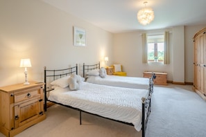 A bedroom with two beds, wooden nightstands, a dresser, and a large wardrobe.