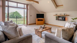 A spacious living room with a large window, a wooden coffee table, and a television. - 3 Bed in Pontardawe (oc-c30415) (Cilybebyll Pontardawe)